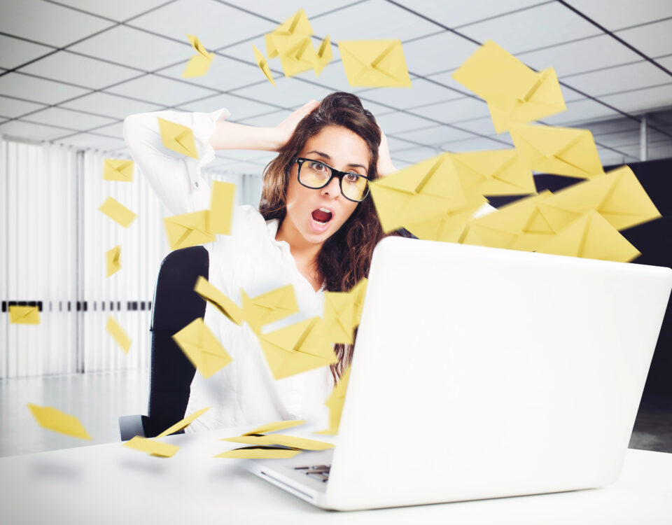 image of envelopes representing email flying out of laptop; woman with shocked face