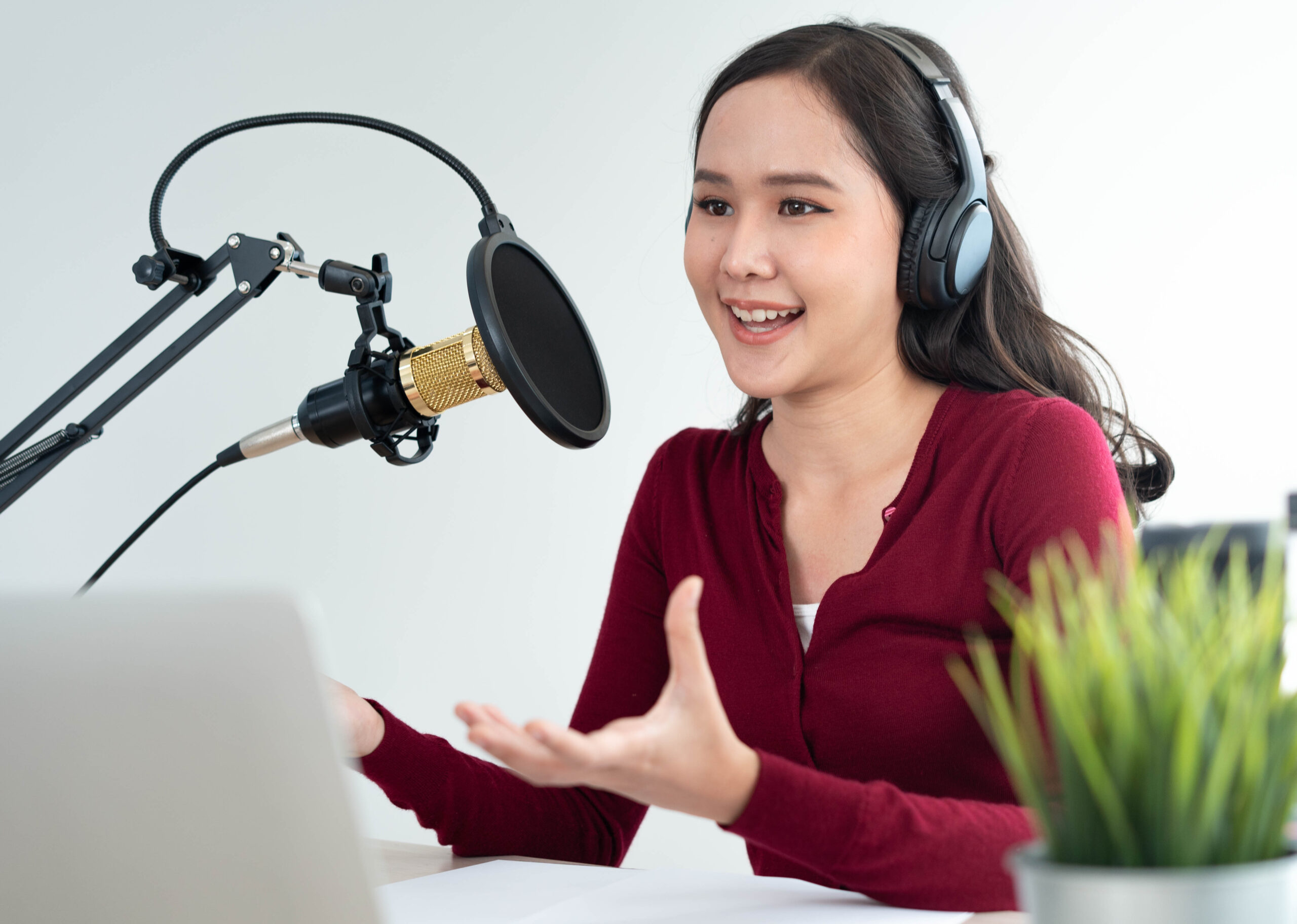 woman wearing headphones and speaking into a microphone recording a podcast episode