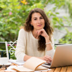 professional woman working on laptop with satisfied smil