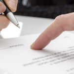 close up of hand signing contract