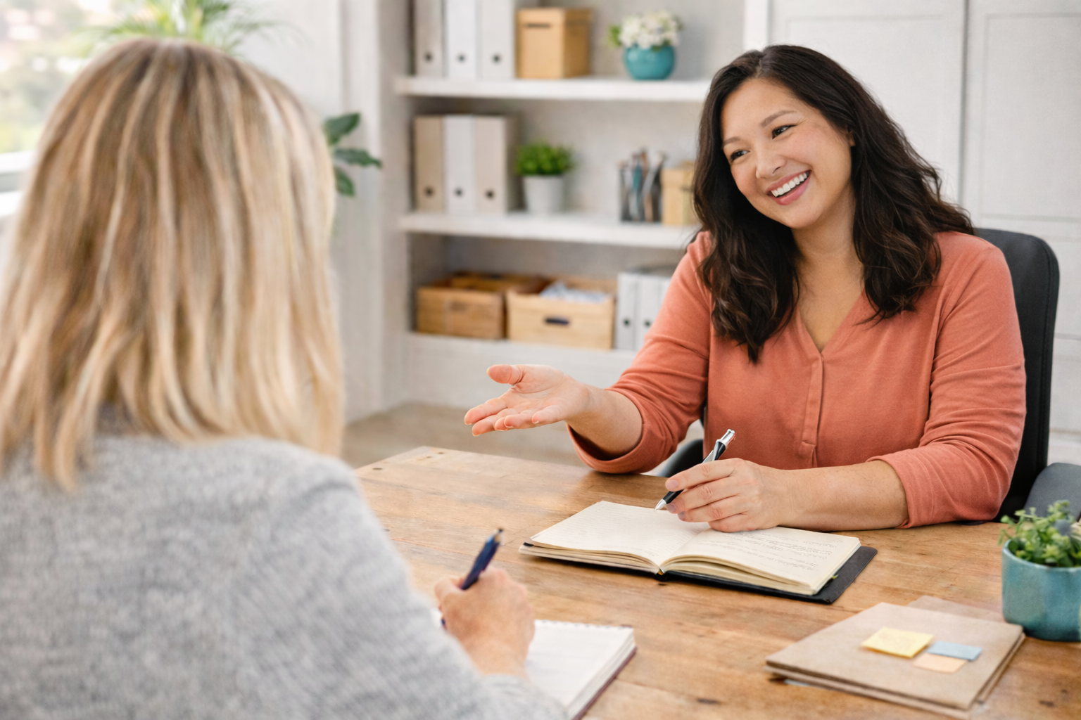 collaborative conversation between two women at wooden desk