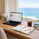 image of desktop with open laptop, notebook, glass of soda, in front of a window overlooking the ocean
